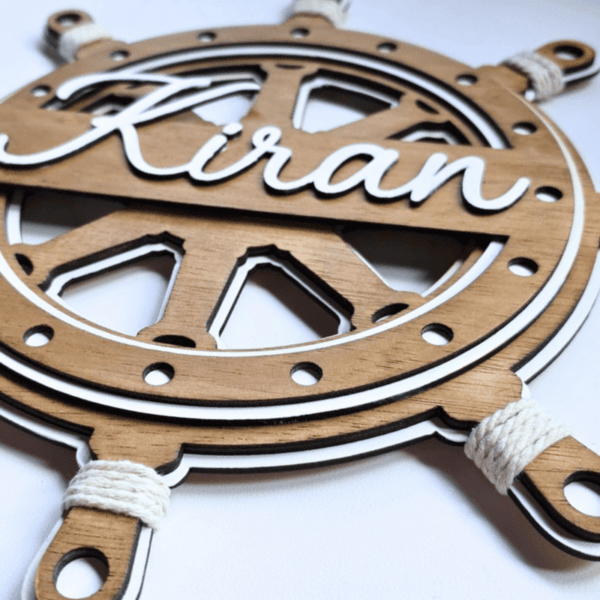 Houten stuurwiel met naam Kirian en touwdetails voor kinderkamer.